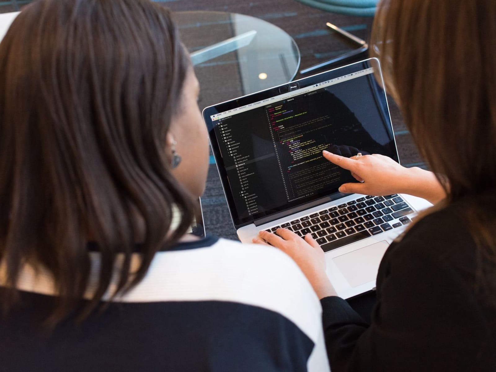 Two students coding together on a laptop in a Genixotech programming class