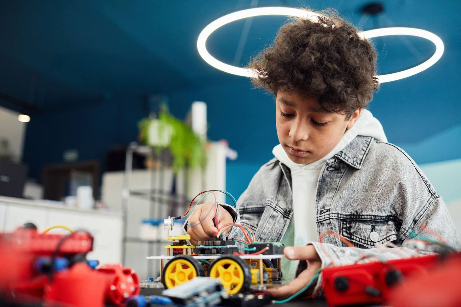 A student building an Arduino robot car in a Genixotech robotics workshop