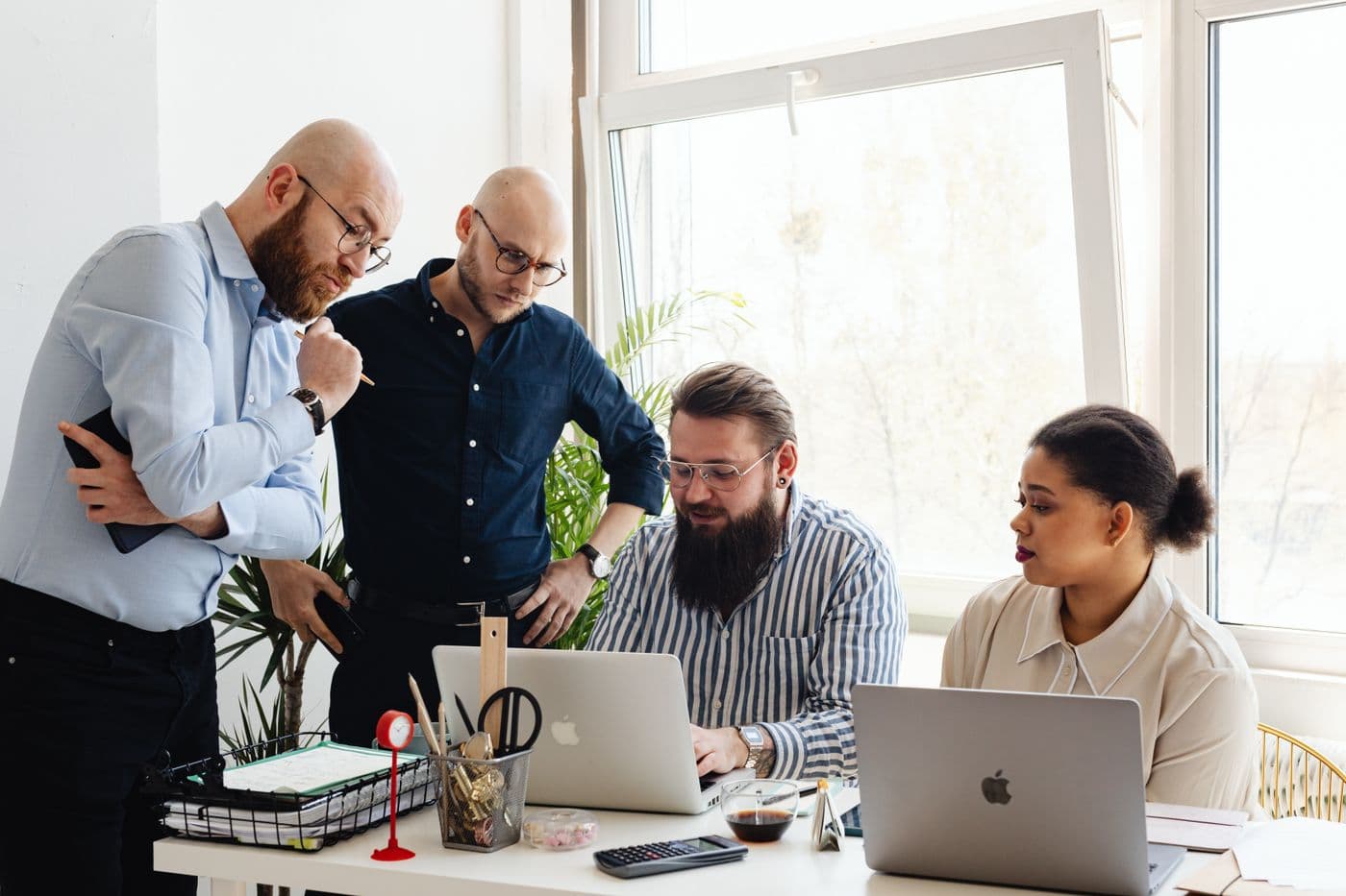 A Genixotech digital team collaborating on laptops in a modern office